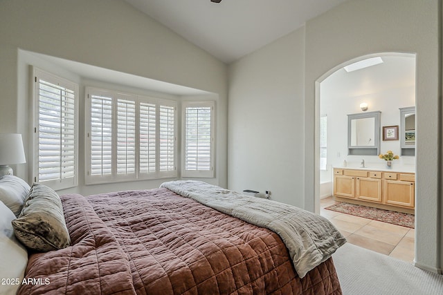 bedroom featuring multiple windows, vaulted ceiling, arched walkways, and light tile patterned flooring