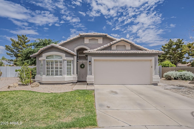 mediterranean / spanish house with fence, a tiled roof, stucco siding, an attached garage, and driveway