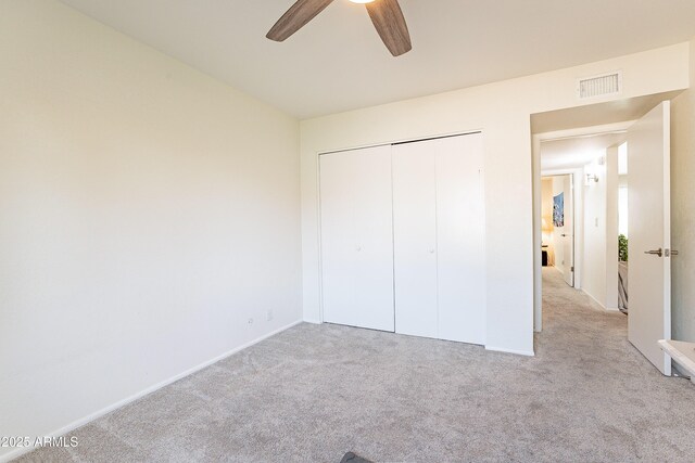 unfurnished bedroom with ceiling fan, a closet, and light carpet