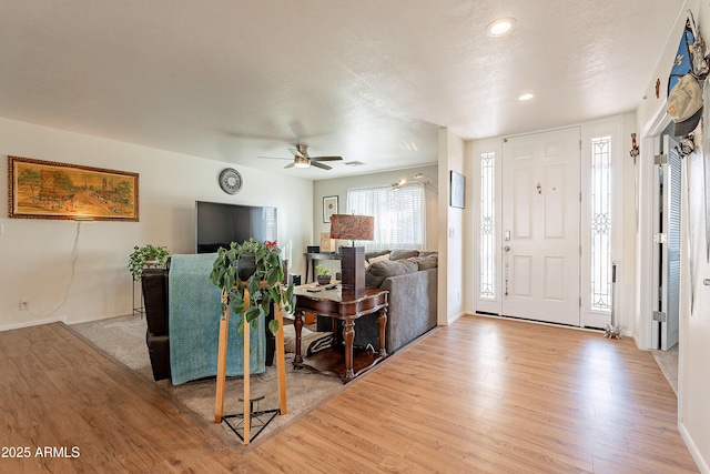 foyer entrance with ceiling fan, light hardwood / wood-style flooring, and a textured ceiling