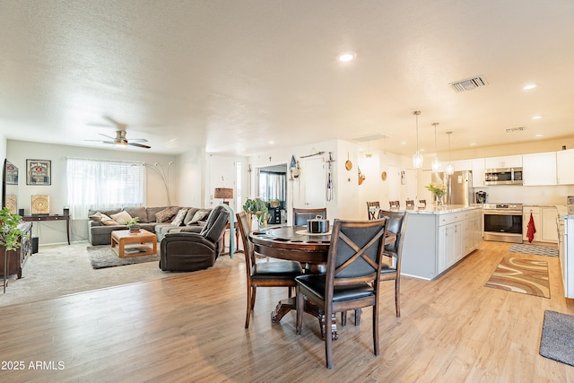 dining room featuring ceiling fan, a textured ceiling, and light wood-type flooring