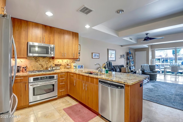 kitchen with sink, light carpet, kitchen peninsula, ceiling fan, and stainless steel appliances