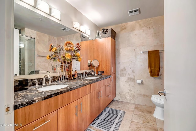 bathroom with vanity, tile walls, and toilet