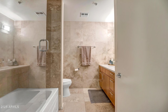 bathroom featuring tile walls, vanity, a bathtub, and toilet