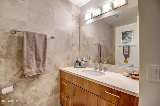 bathroom featuring vanity, tile walls, and toilet