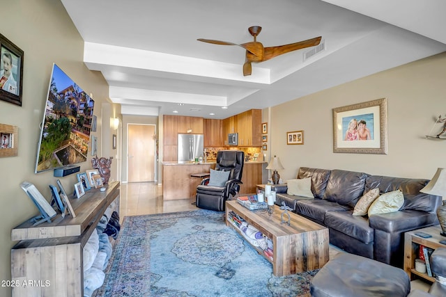 living room with ceiling fan and a tray ceiling