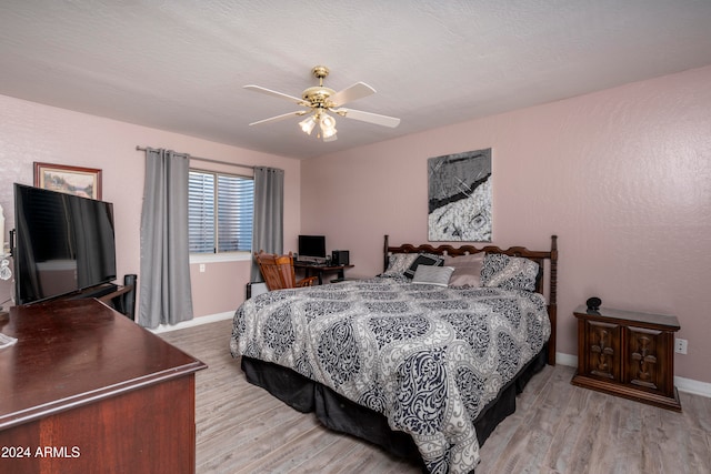 bedroom featuring ceiling fan, light hardwood / wood-style floors, and a textured ceiling