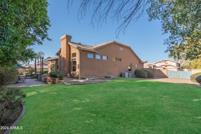 back of house with a lawn and a patio