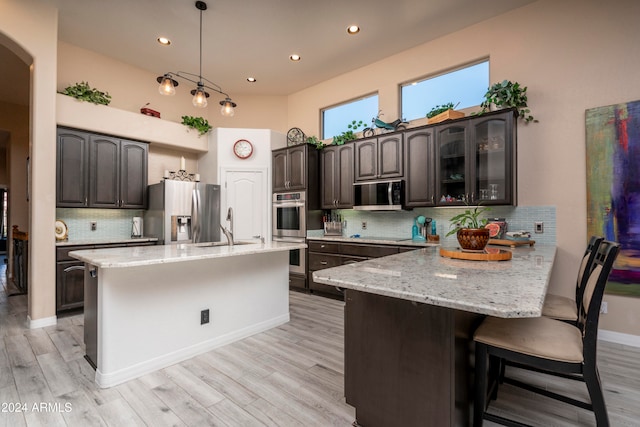 kitchen featuring backsplash, sink, light hardwood / wood-style flooring, appliances with stainless steel finishes, and dark brown cabinets