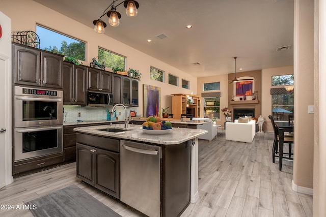 kitchen featuring appliances with stainless steel finishes, dark brown cabinets, a kitchen island with sink, and sink