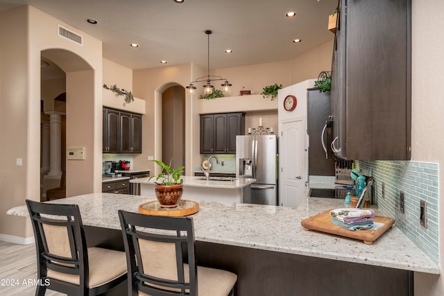 kitchen with sink, light hardwood / wood-style flooring, a kitchen island, light stone counters, and stainless steel fridge with ice dispenser