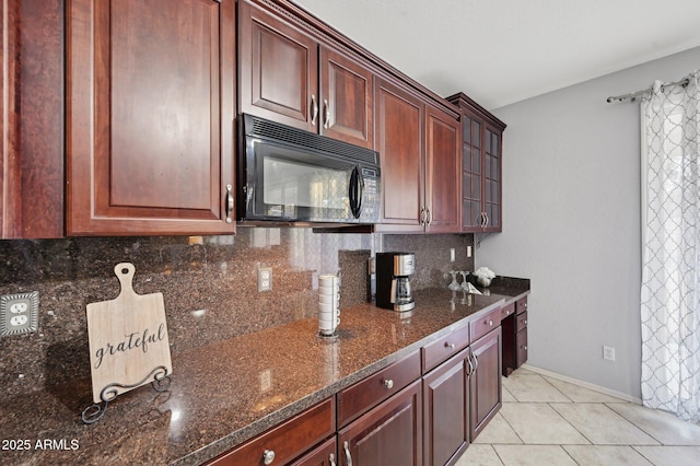 kitchen with dark stone countertops, backsplash, and light tile patterned floors