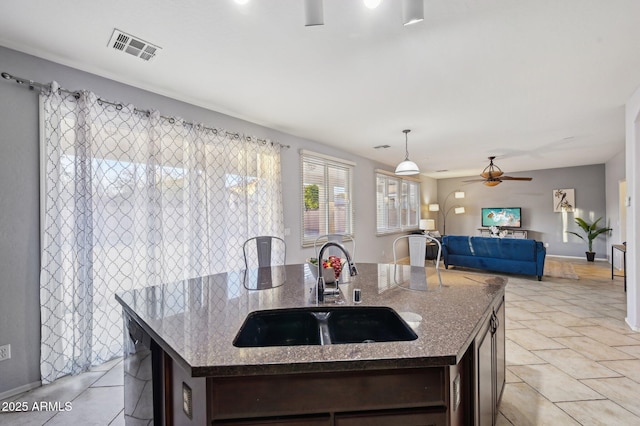 kitchen with an island with sink, dark brown cabinets, and sink