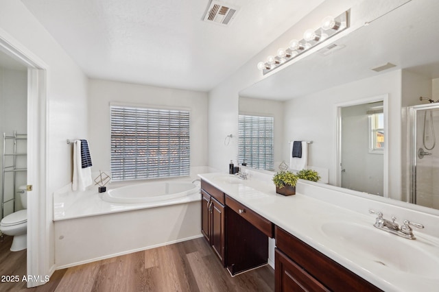 full bathroom with hardwood / wood-style flooring, vanity, toilet, and plus walk in shower