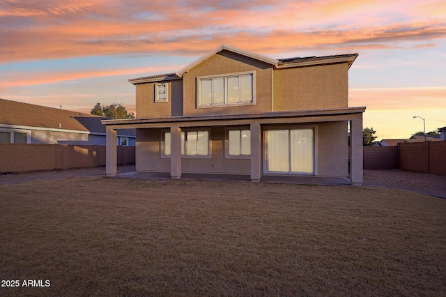 back house at dusk featuring a patio area