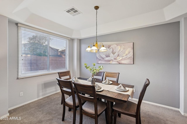 dining space with a tray ceiling, carpet flooring, and a chandelier