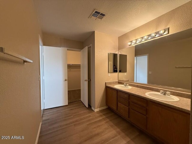 bathroom with hardwood / wood-style flooring, vanity, and a textured ceiling