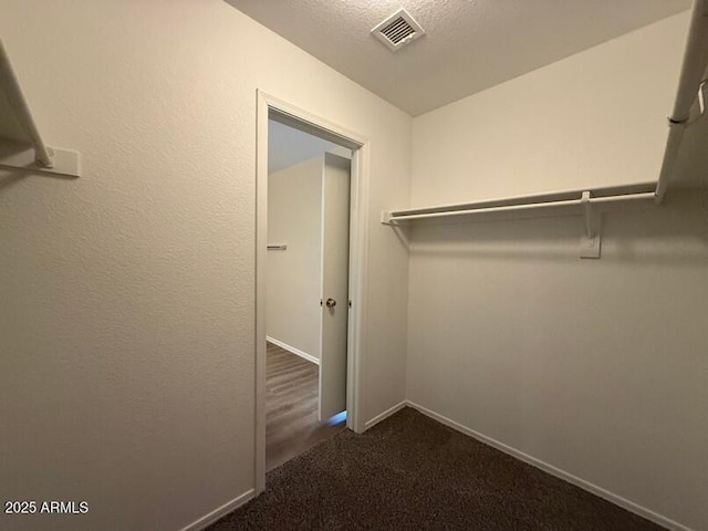 walk in closet featuring dark colored carpet