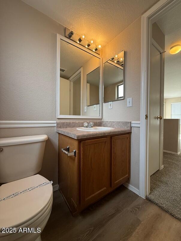 bathroom with vanity, a textured ceiling, wood-type flooring, and toilet