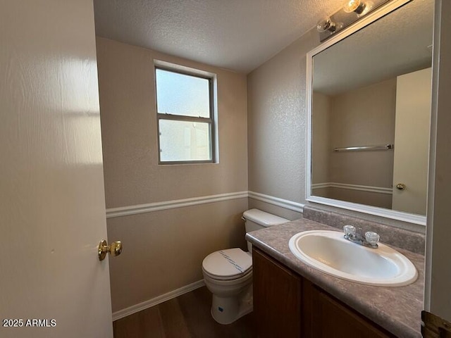 bathroom with hardwood / wood-style flooring, vanity, a textured ceiling, and toilet