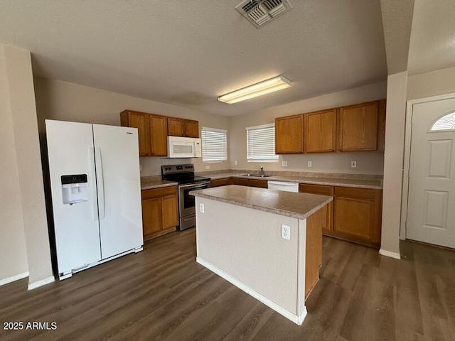 kitchen with sink, a center island, a textured ceiling, dark hardwood / wood-style floors, and white appliances