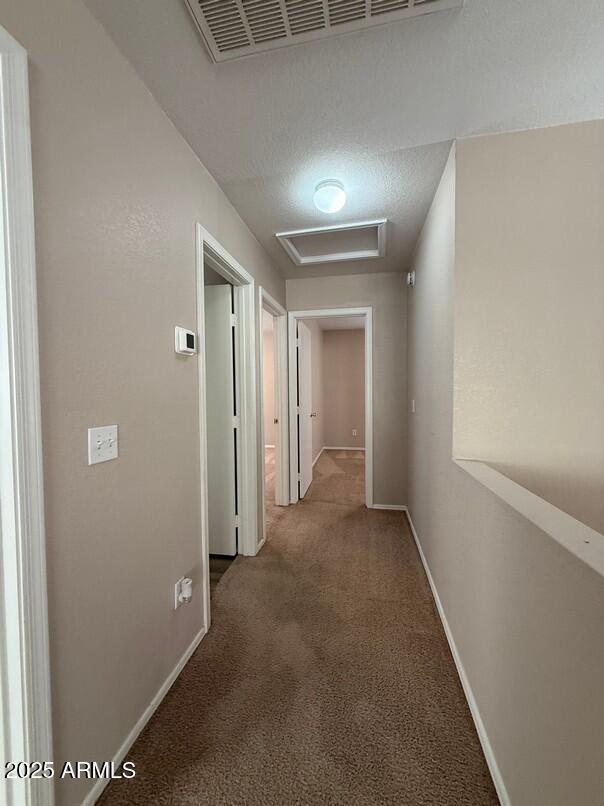 corridor with carpet floors and a textured ceiling