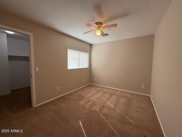 unfurnished bedroom featuring carpet floors, a spacious closet, a textured ceiling, and ceiling fan