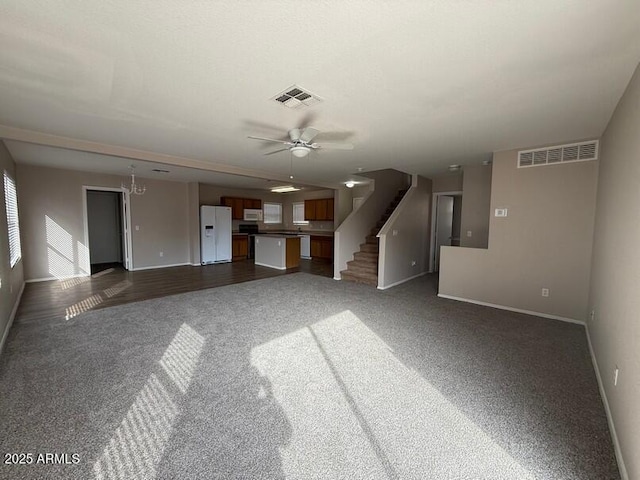 unfurnished living room with ceiling fan and dark colored carpet