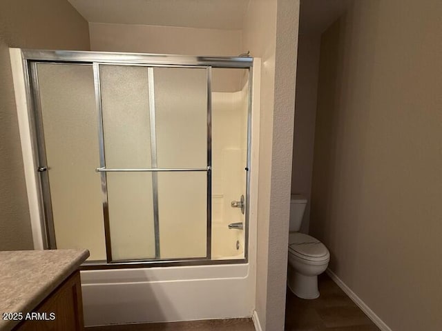 full bathroom with vanity, bath / shower combo with glass door, and toilet