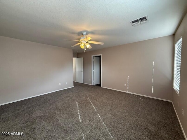 spare room with ceiling fan and dark colored carpet