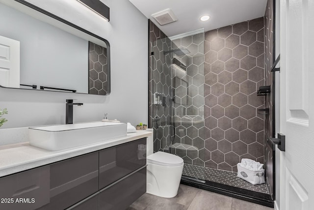 bathroom with tiled shower, tile patterned floors, vanity, and toilet