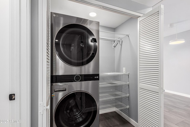 clothes washing area featuring hardwood / wood-style floors and stacked washing maching and dryer