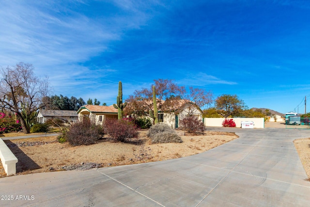 view of front of house with fence, a tiled roof, and stucco siding