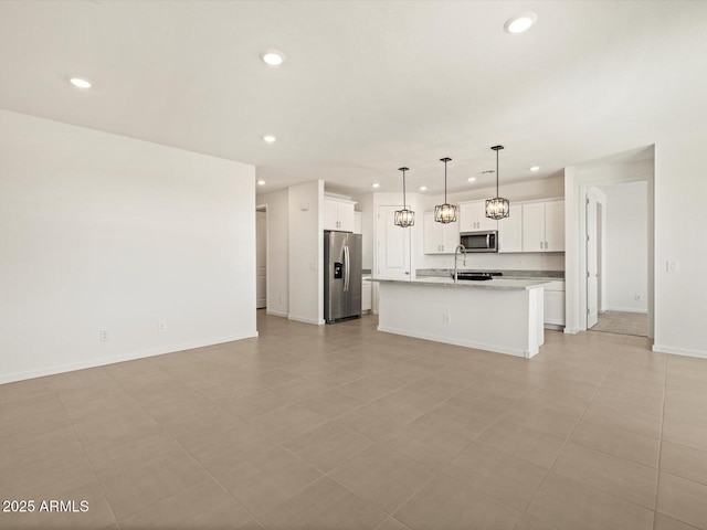 kitchen with pendant lighting, recessed lighting, appliances with stainless steel finishes, a kitchen island with sink, and white cabinetry