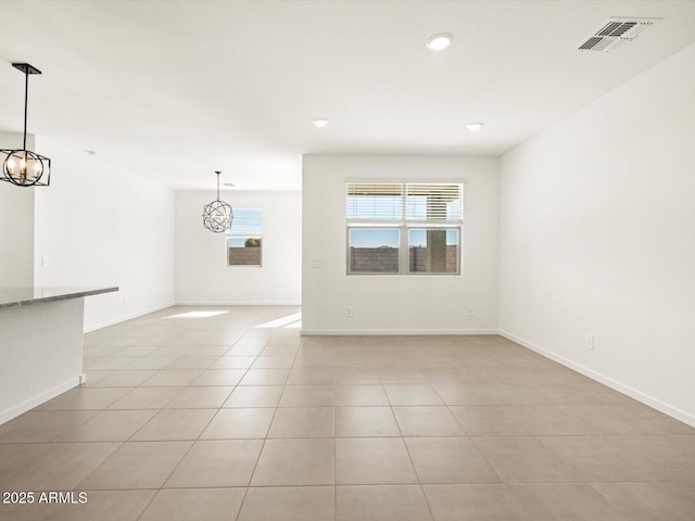 unfurnished room with light tile patterned floors, an inviting chandelier, visible vents, and baseboards