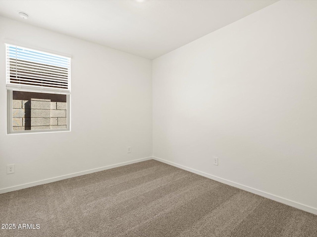 spare room featuring carpet and baseboards