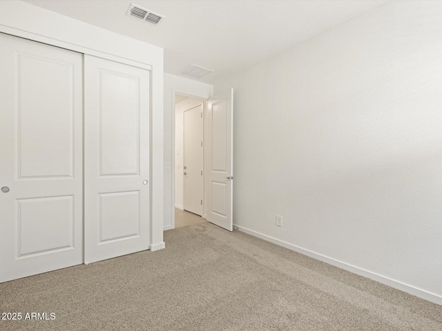 unfurnished bedroom featuring baseboards, visible vents, a closet, and light colored carpet