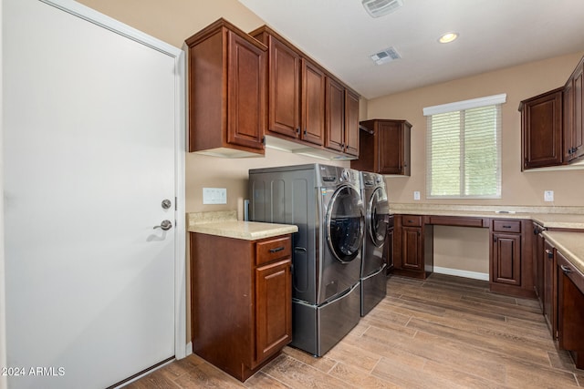 laundry area with light hardwood / wood-style floors, washing machine and dryer, and cabinets