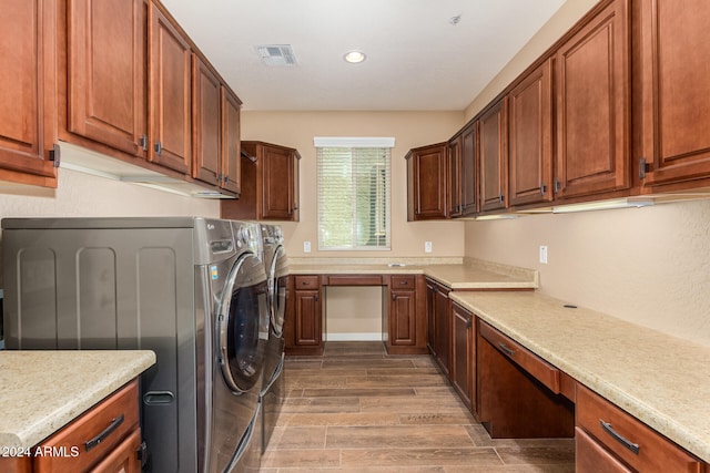 clothes washing area featuring wood-type flooring, cabinets, and washer and dryer