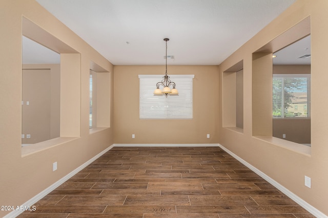 unfurnished dining area featuring dark wood-type flooring and a chandelier