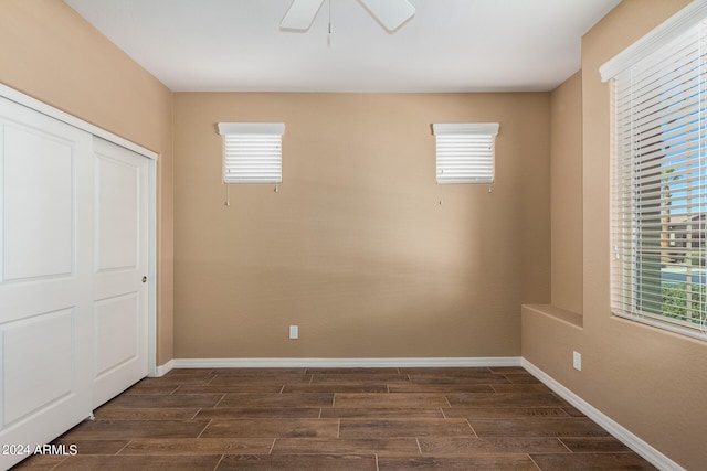 unfurnished bedroom featuring ceiling fan, dark wood-type flooring, and multiple windows