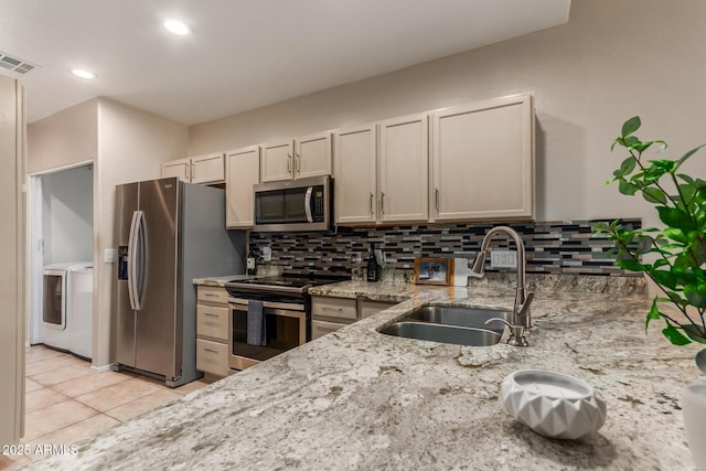 205 N 74th St Unit 166, Mesa, AZ 85207 - kitchen with stainless steel appliances, washer and dryer, tasteful backsplash, light stone counters, and light tile patterned flooring