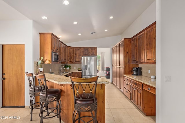 kitchen featuring a breakfast bar area, light tile patterned floors, light stone counters, kitchen peninsula, and stainless steel appliances