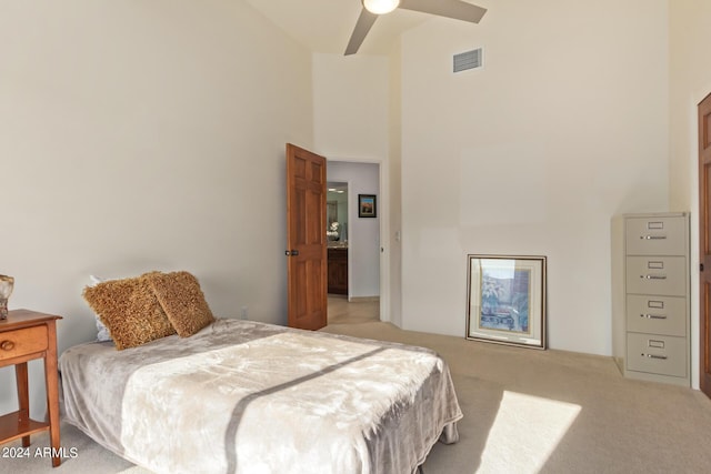 bedroom featuring ceiling fan, light carpet, and a high ceiling