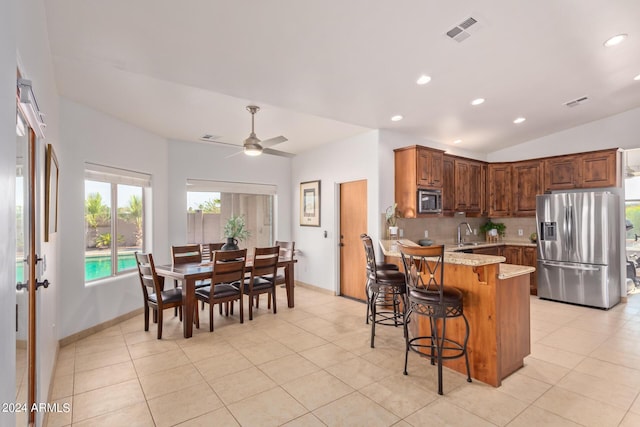 kitchen featuring appliances with stainless steel finishes, tasteful backsplash, a kitchen breakfast bar, light stone counters, and kitchen peninsula