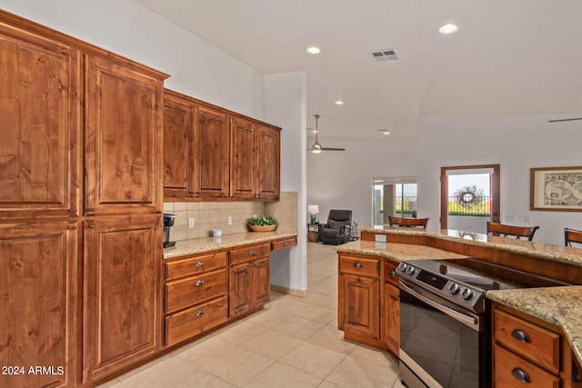 kitchen with decorative backsplash, light tile patterned floors, electric range, ceiling fan, and light stone counters