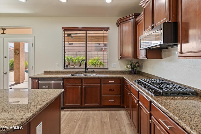 kitchen with light stone countertops, appliances with stainless steel finishes, sink, and light wood-type flooring