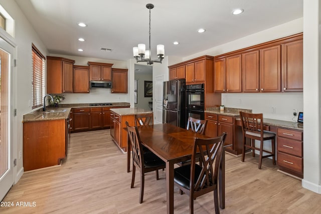 kitchen featuring sink, hanging light fixtures, a center island, light hardwood / wood-style floors, and black appliances