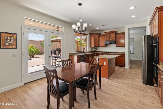 dining room with sink, a notable chandelier, light wood-type flooring, and french doors