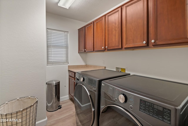 laundry room featuring washer and clothes dryer, light hardwood / wood-style floors, and cabinets